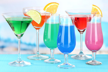 Glasses of cocktails on table near pool