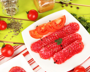Tasty salami on plates on wooden table close-up