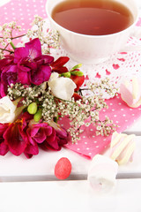 Fototapeta na wymiar Piękna kompozycja z filiżanką herbaty i kwiaty