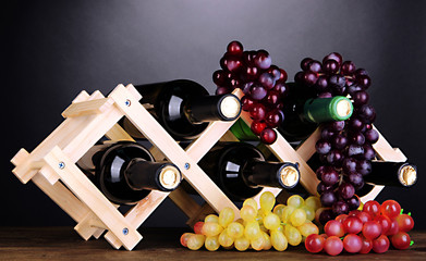 Bottles of wine placed on wooden stand on grey background