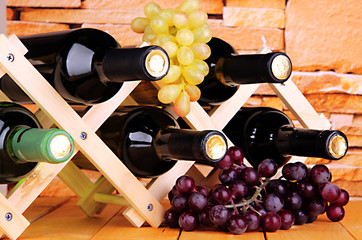 Bottles of wine placed on wooden stand on stone wall background