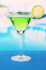 Green cocktail with lime on table on bright background