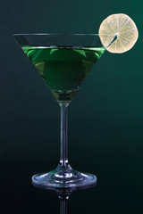 Green cocktail with lime on dark green background