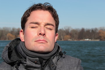 Mann relaxt im Winter im Sonnenschein am See
