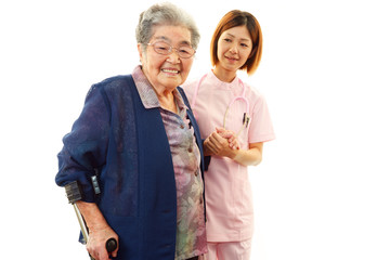 介護士と手をつなぎ歩く高齢者