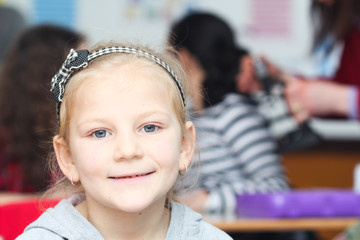 Happy little girl in school with her friends arround
