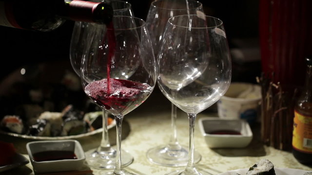 Red wine is poured in the glasses.