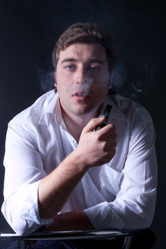 portrait of the young beautiful man smoking a pipe