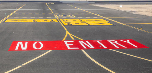 no entry sign at the runway of the airport with ocean in backgro