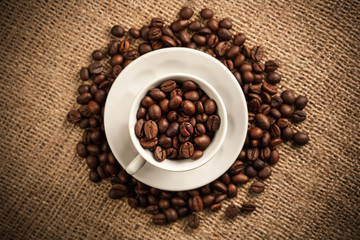 Fototapeta na wymiar Roasted coffee beans in a cup on burlap background