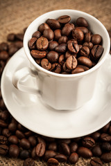 Roasted coffee beans in a cup on burlap background