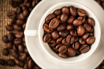 Roasted coffee beans in a cup on burlap background