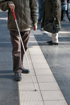 Blind person with white cane in public space