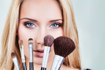 closeup of woman's face and makeup brushes