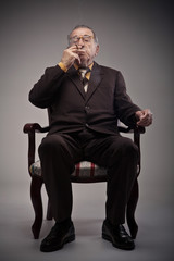 Old man sitting in a chair and smoking a cigarette