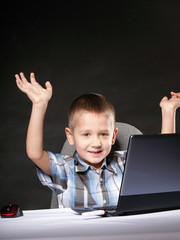 Triumphing child with a laptop computer