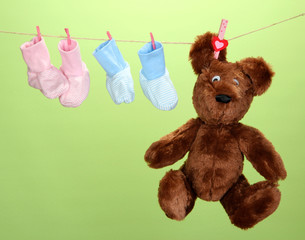 Plakat Baby booties hanging on clothesline, on color background