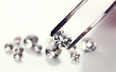 Beautiful shining crystal (diamond) in the tweezers, isolated