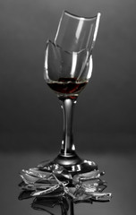 Broken wineglass on grey background