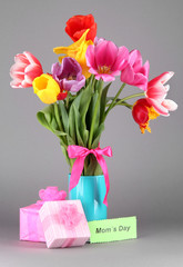 Beautiful tulips in bouquet with gifts and note