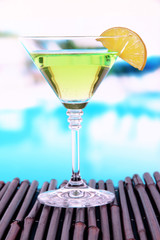 Green cocktail with lime on table on bright background