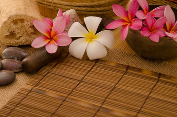 Obraz na płótnie Canvas tropical spa setup with frangipani flower hot rocks and massage