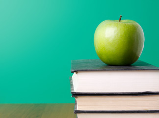 Green apple on a pile of book, isolated on green background