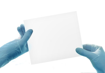 Hands in medical gloves with paper sheet over white background.