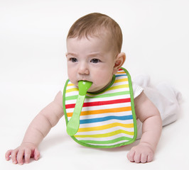Baby with spoon in mouth looking aside