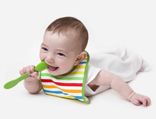 Smiling infant baby with spoon in mouth
