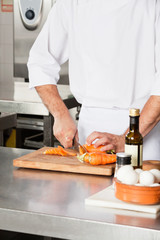 Chef Cutting Carrots At Kitchen Counter