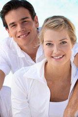 Smiling young couple dressed in white on a summer's day