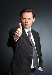 Businessman with his thumb up. Focus is on person, thumb is slig