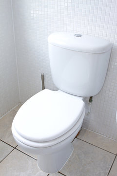 white toilet in a clean white tiled bathroom