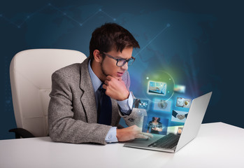 Young man sitting at desk and watching his photo gallery on lapt