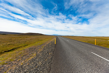 Fototapeta na wymiar Highway through Icelandic landscape under a blue summer sky with