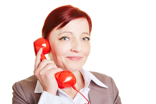 Gl&uuml;ckliche Gesch&auml;ftsfrau mit rotem Telefonh&ouml;rer