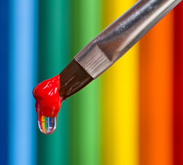 Brush with a drop of paint on a multicolored background