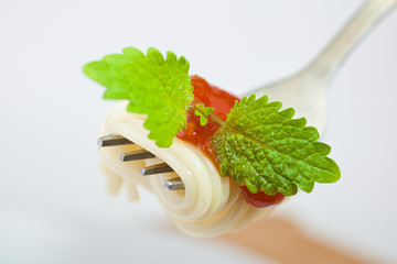 Spaghetti on fork with ketchup and greens