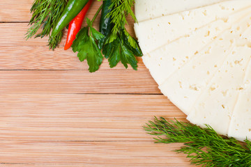 Sliced cheese with herbs on a wooden surface