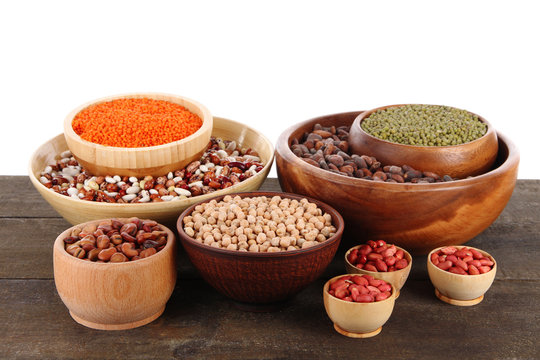 Different kinds of beans in bowls on table isolated on white