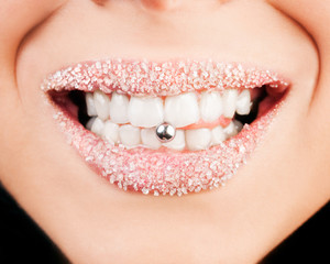 Smiling lips with sugar showing piercing