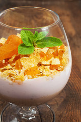 dessert with muesli , yogurt and dried apricots in a glass