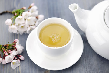 Obraz na płótnie Canvas Cup of green tea and japanese cherry blossom