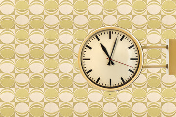 Seventies vintage office clock against a retro wallpaper back