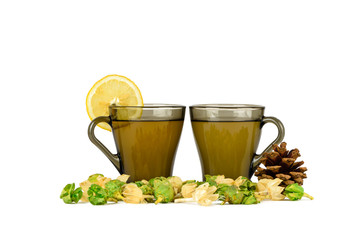 Two cups of green tea with lemon, fir-cone and physalis