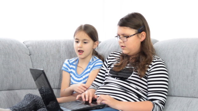 Two sister using a laptop in the living room