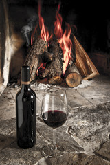 Copa de vino tino con fuego de chimenea de fondo.