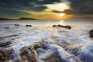 Sea waves lash line impact rock on the beach