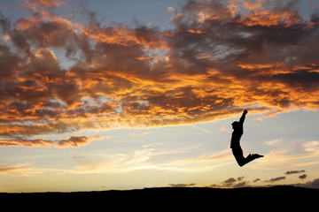 silhouette of teen jumping in sunset for fun